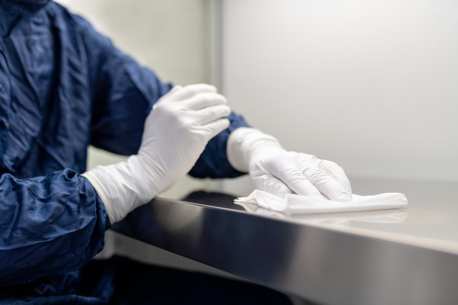 Gloved cleaner wiping a stainless steel surface